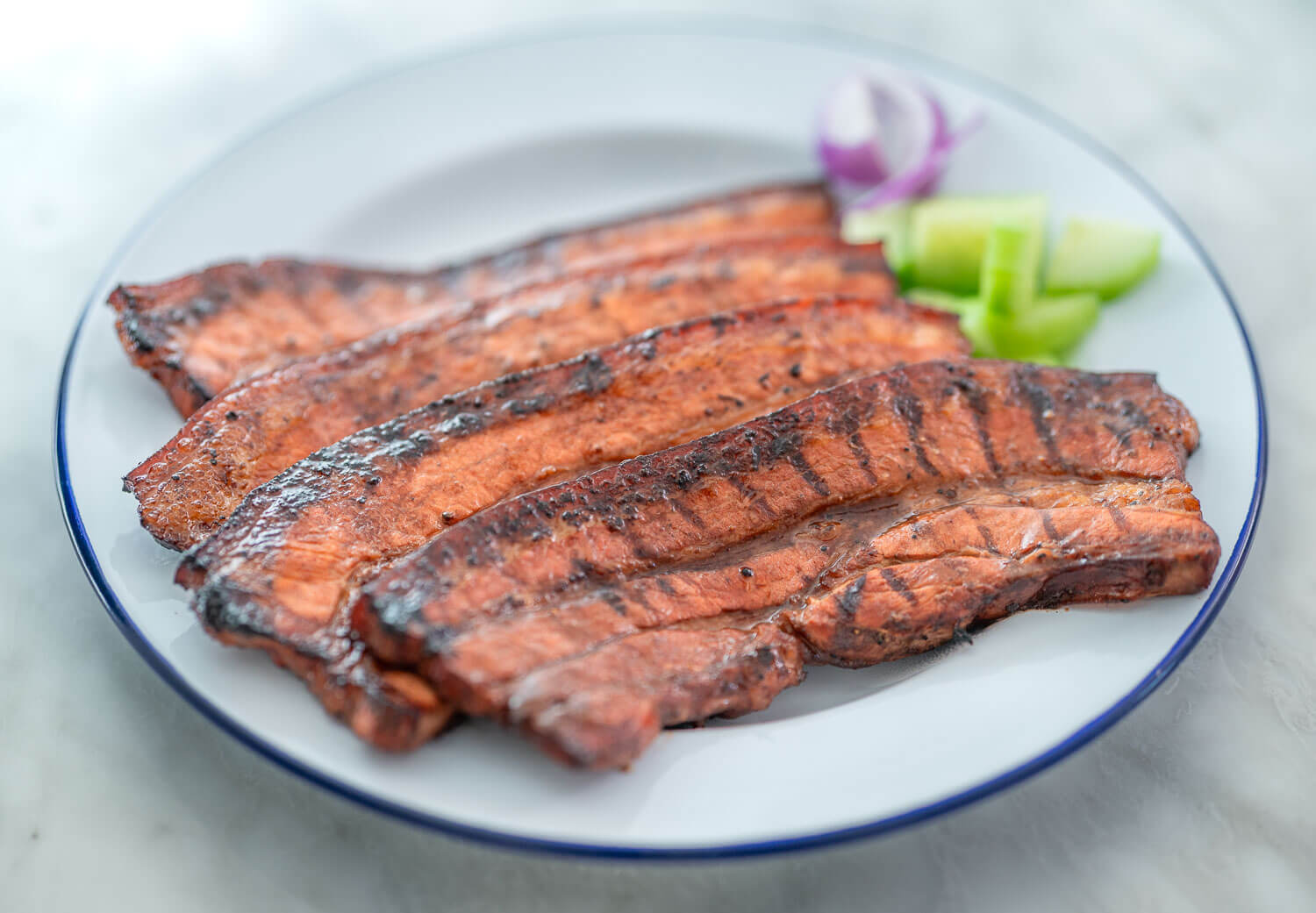 inihaw na liempo with a side of fresh cucumbers and onion