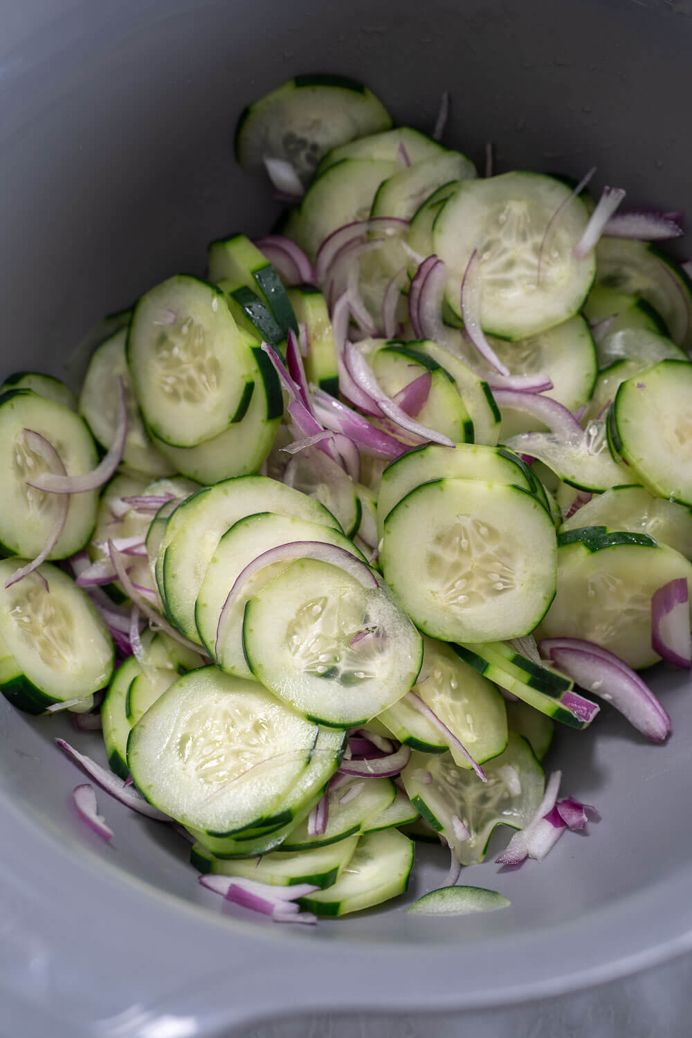 Sliced cucumber and onion in a mixing bowl