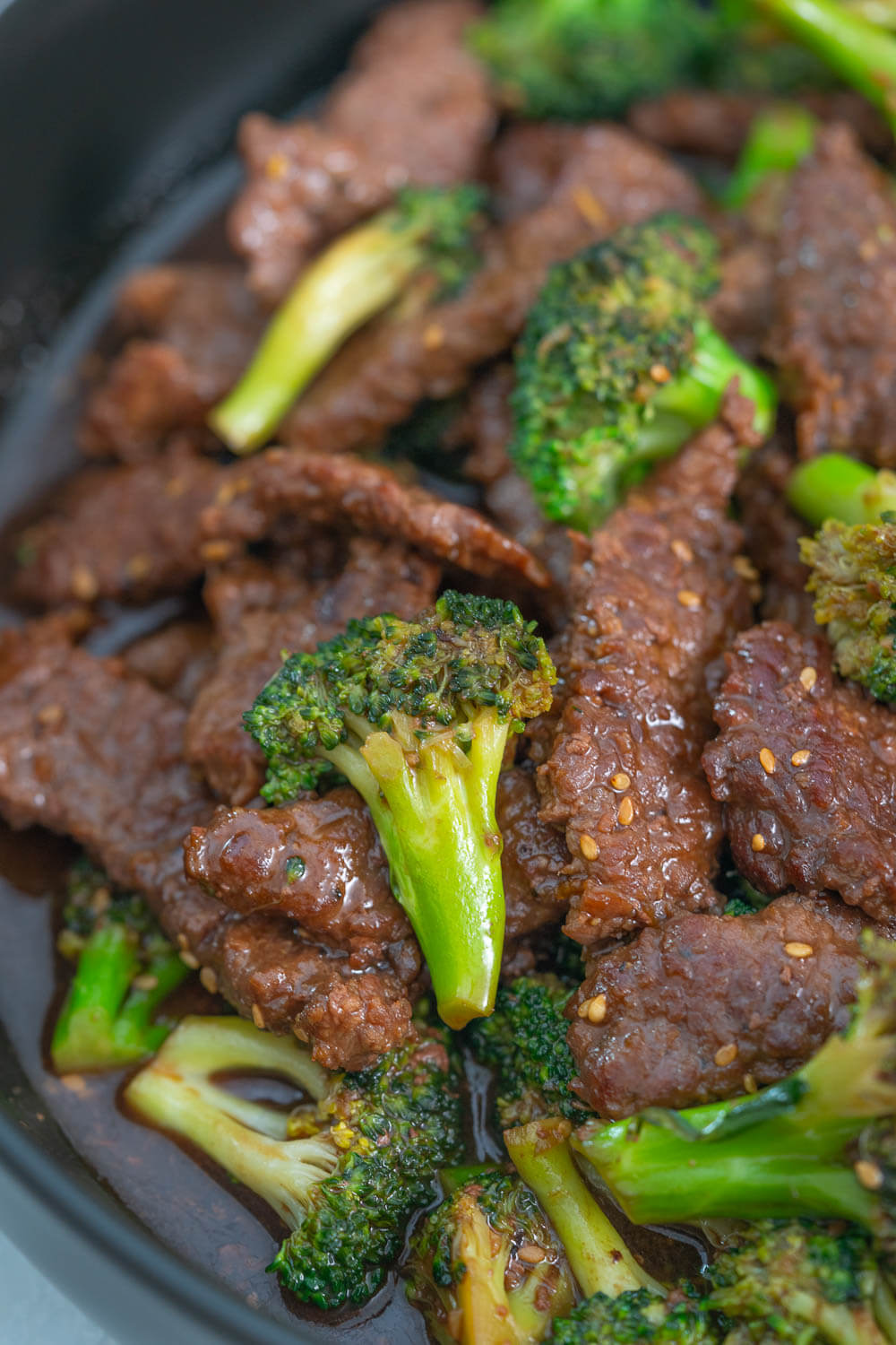 A piece of broccoli floret sitting on a slice of beef