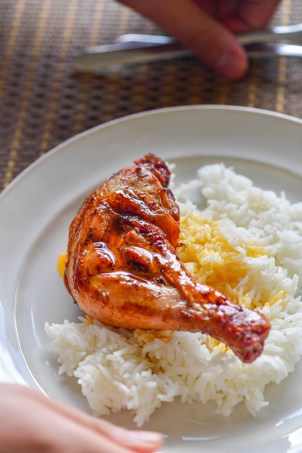 Chicken inasal leg quarter over rice on a plate