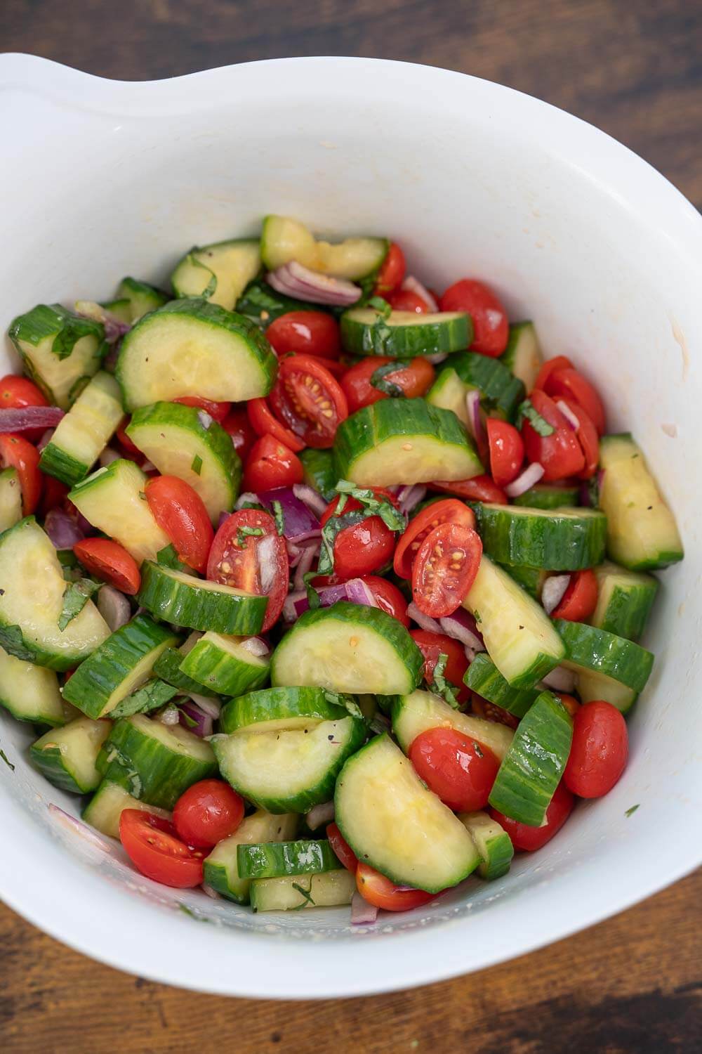 Ingredients for cucumber salad in a bowl for tossing