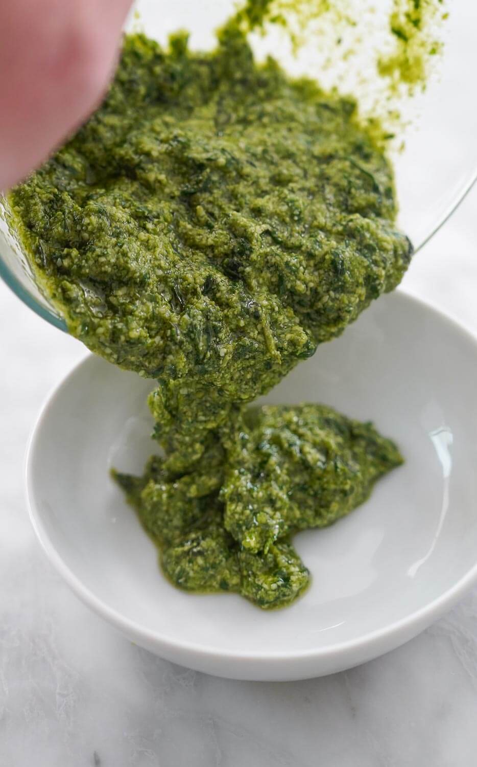 Basil pesto being transferred to a bowl